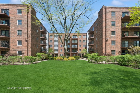 Front view of a multi-story brick apartment building with balconies.