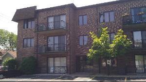 Front view of a three-story brick residential building with balconies.