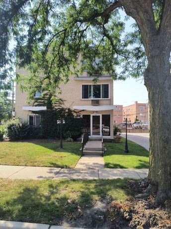 Front view of a three-story brick building with a pathway leading to the entrance.