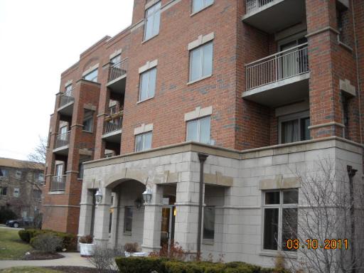Front view of a multi-story brick apartment building with balconies.