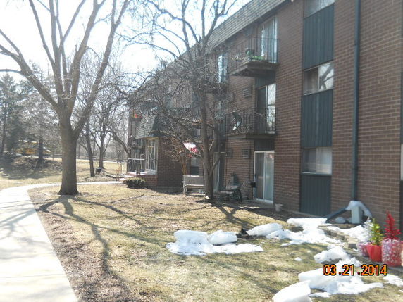 Side view of a multi-story brick apartment building with balconies.