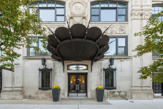 Front view of a building with ornate architectural details and a decorative black awning.