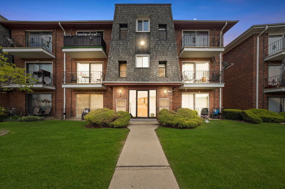 Front view of a multi-story brick apartment building with balconies.