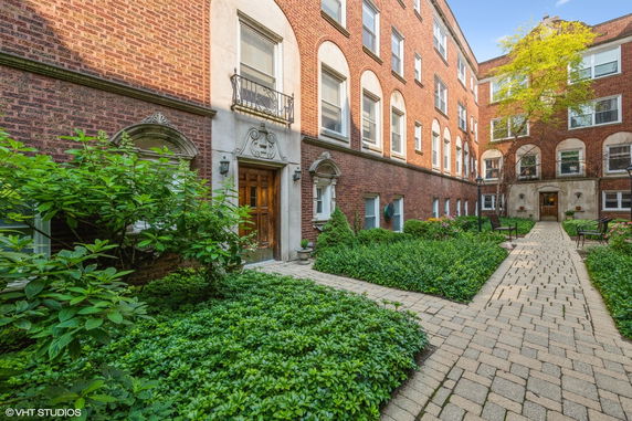 Front view of a brick multi-story building with a courtyard.