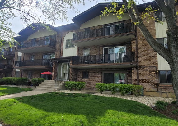 Front view of a multi-story brick apartment building with balconies.