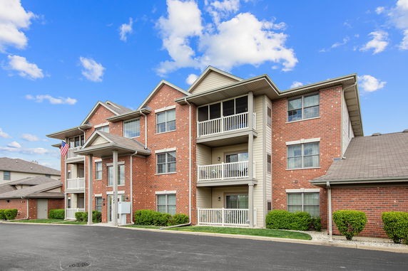 Front view of a three-story brick apartment building with balconies.