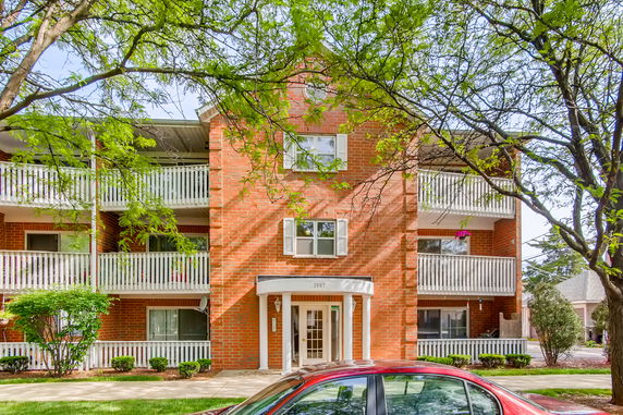Front view of a multi-story brick apartment building with balconies.