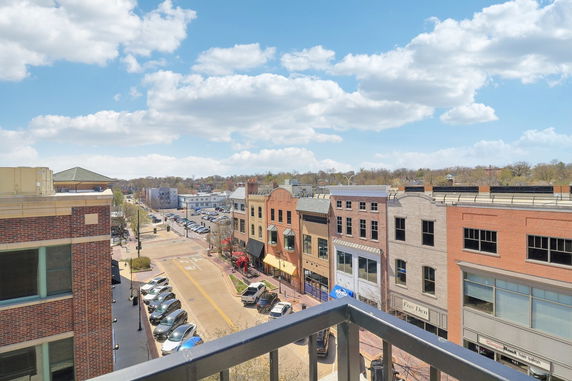 Panoramic view from a building showing a street with parked cars and multiple buildings.