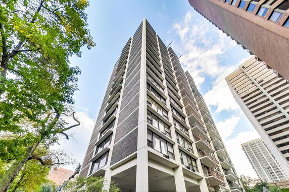 Front view of a tall residential building with multiple balconies.