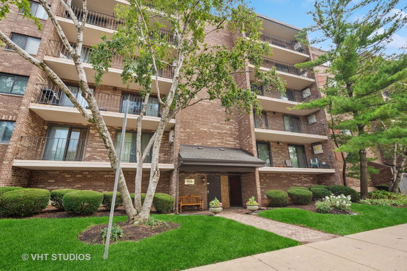 Front view of a multi-story brick apartment building with balconies.