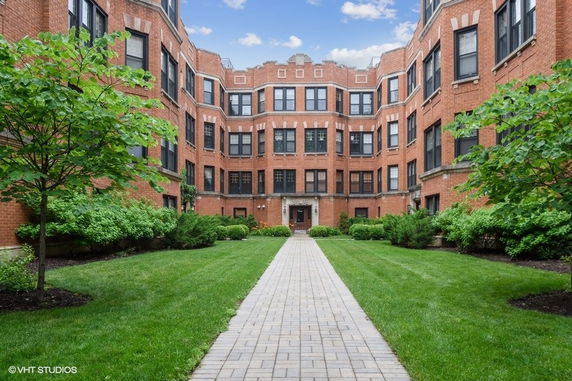 Front view of a multi-story brick building with a central entrance and symmetrical windows.