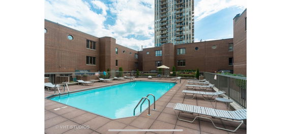 Outdoor swimming pool area with lounge chairs next to a building.