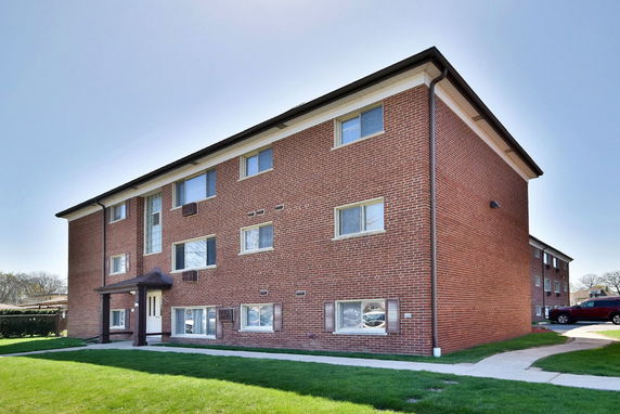 Front view of a three-story brick apartment building with multiple windows.
