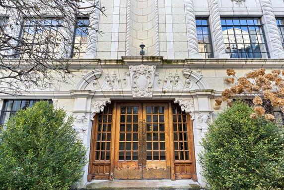 Front view of a stone facade building with ornate detailing and wooden double doors.