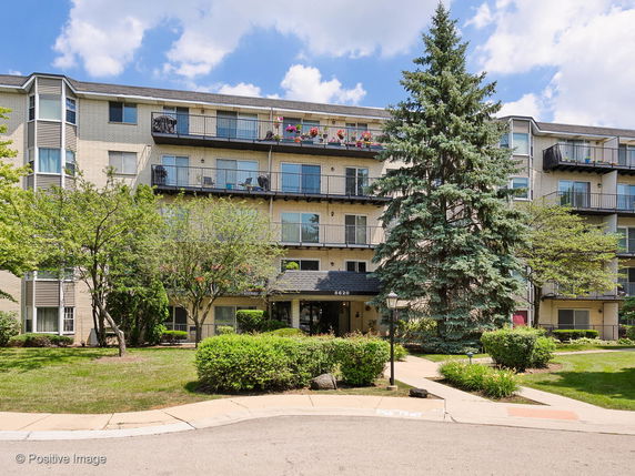 Front view of a multi-story residential building with balconies and a central entrance.