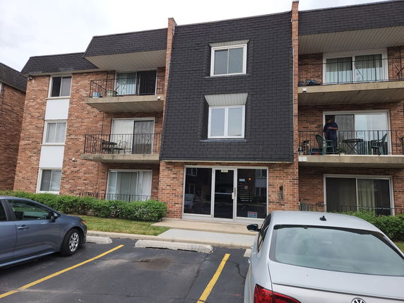 Front view of a multi-story brick apartment building with balconies.