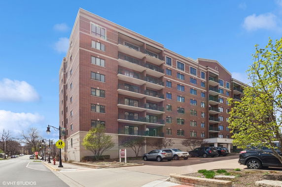 Front view of a multi-story brick apartment building with balconies.
