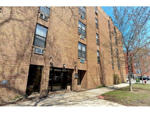 Front view of a multi-story brick building with several windows.