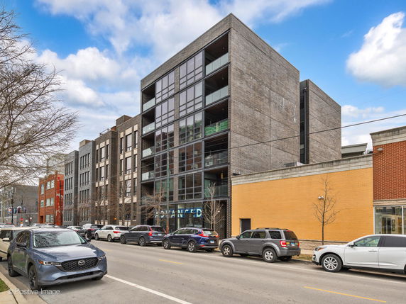 Front view of a modern multi-story building with large glass windows.