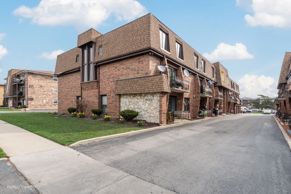 Front view of a brick apartment building with balconies.