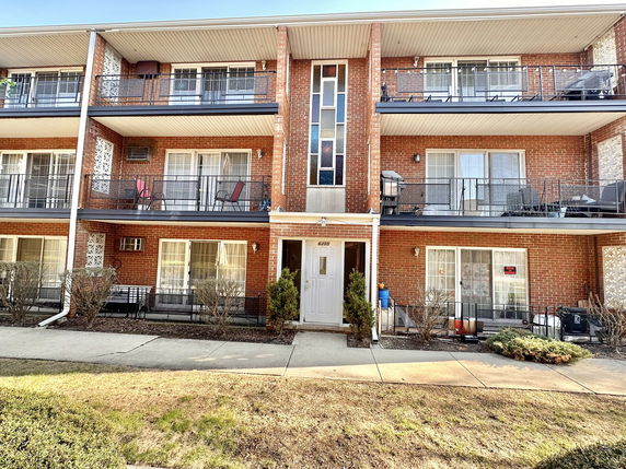Front view of a multi-story brick apartment building with balconies.