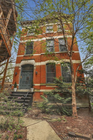 Front view of a multi-story brick house with a central entrance.