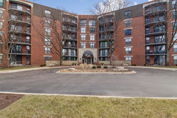 Front view of a multi-story brick apartment building with balconies.