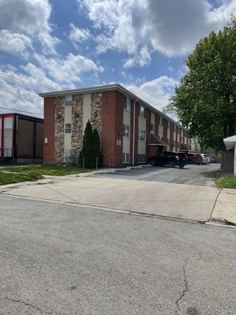 Front view of a two-story brick building with parking area.