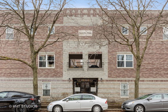 Front view of a multi-story brick building with multiple windows and a gated entrance.