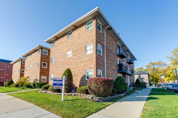 Front view of a multi-story brick apartment building with balconies.