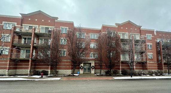 Front view of a multi-story brick apartment building with balconies.
