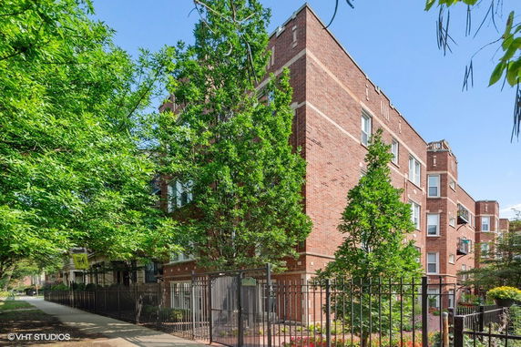 Front view of a brick apartment building with multiple floors and windows.