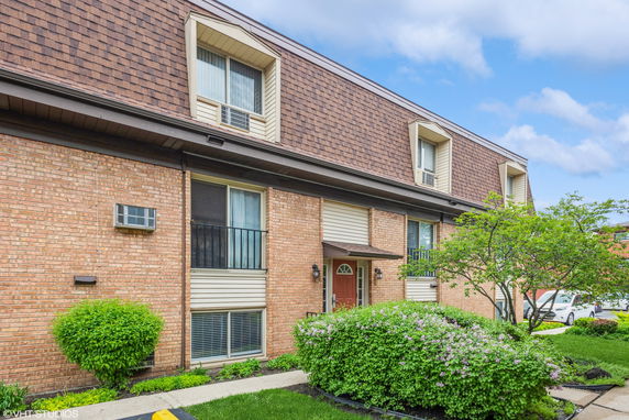 Front view of a multi-story brick building with dormer windows.