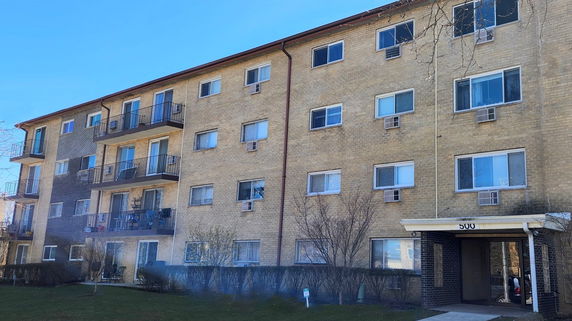 Front view of a multi-story apartment building with balconies and multiple windows.