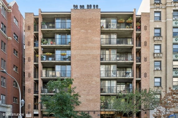 Front view of a multi-story brick residential building with balconies.