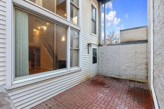 Exterior view of a house with large windows and a brick patio.