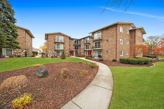 Front view of a multi-story brick apartment building with balconies.