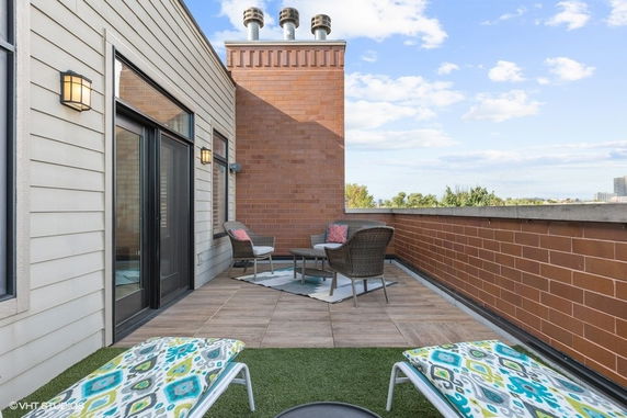 Rooftop area with brick wall, seating, and lounge chairs.