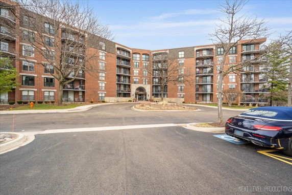Front view of a multi-story brick apartment building with balconies.