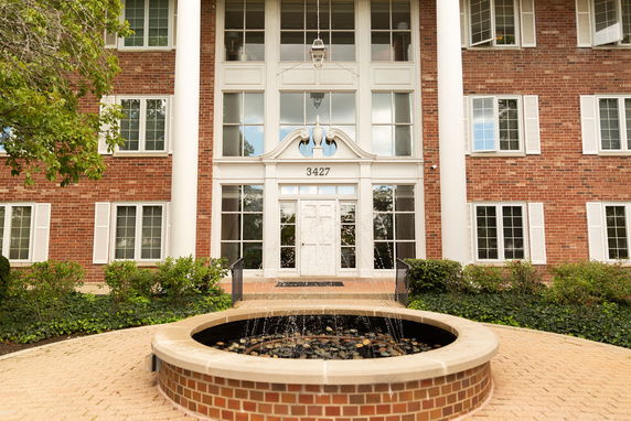 Front view of a multi-story brick building with a central entrance and white columns.