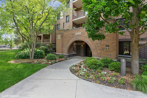 Front view of a multi-story brick building with arched entrance and balconies.