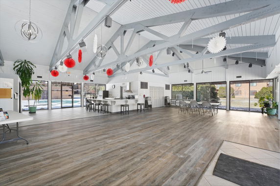 Spacious community room with large windows, decorated with red and white ornaments.