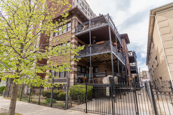 Front view of a brick multi-story building with balconies.