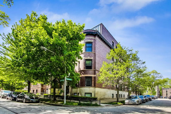 Front and side view of a multi-story brick building with large windows.