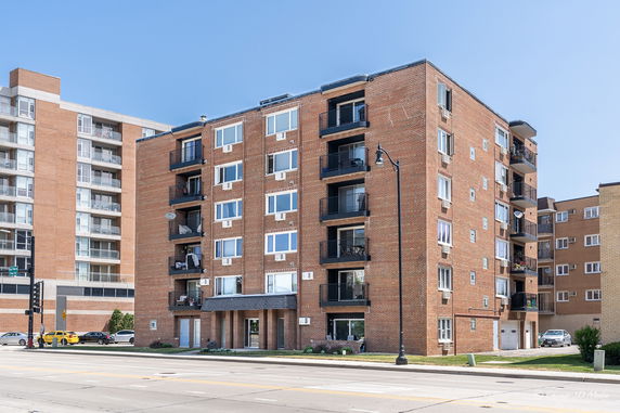 Front view of a multi-story brick apartment building with balconies.