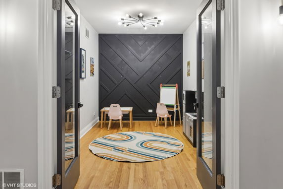 Indoor children's play area with small tables, chairs, and a toy kitchen set.
