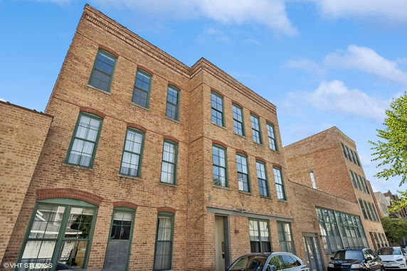 Front view of a three-story brick building with multiple windows.
