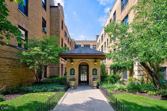 Front view of a multi-story brick building with landscaped entrance.