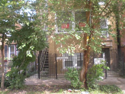 Front view of a multi-story building with a fenced entrance and external staircase.