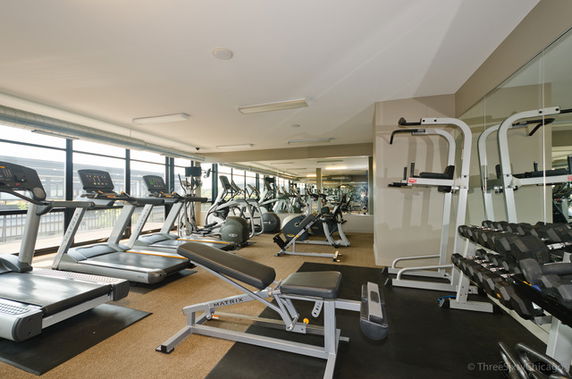 Indoor gym with various exercise equipment including treadmills, stationary bikes, and weights.